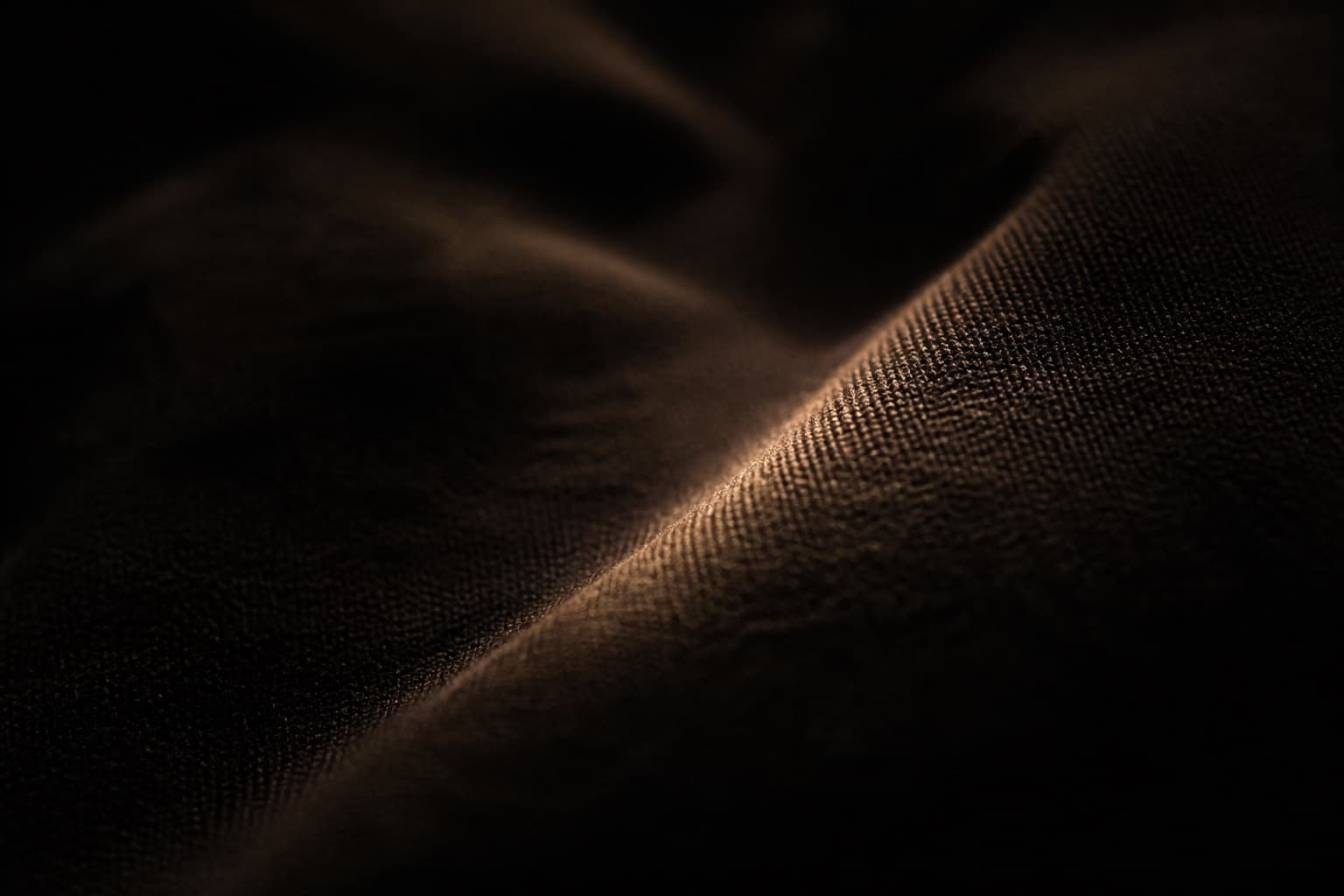 Heavy black cotton, one crease catching a thin warm light