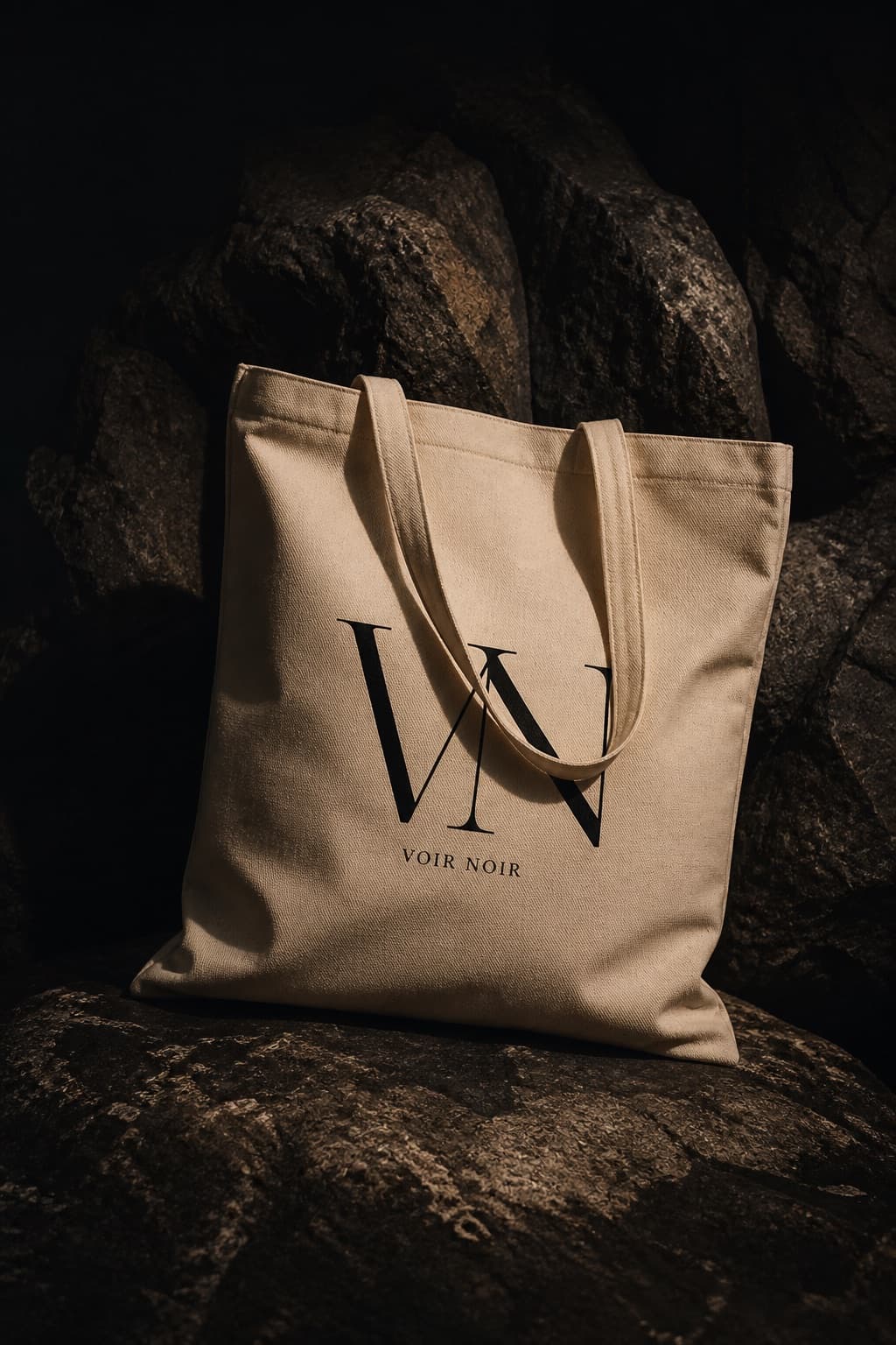 Natural cotton tote standing on dark limestone, black house mark, long handles falling